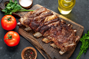 pork ribs with spices, tomatoes and herbs on a stone background