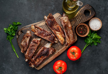 pork ribs with spices, tomatoes and herbs on a stone background
