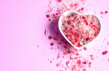 himalayan pink salt on pink paper background in a heart shape saucer