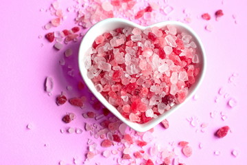 himalayan pink salt on pink paper background in a heart shape saucer