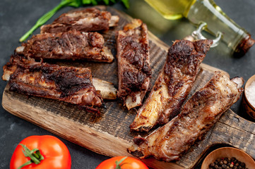 pork ribs with spices, tomatoes and herbs on a stone background