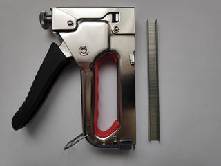 Stapler and staples. On a gray background.