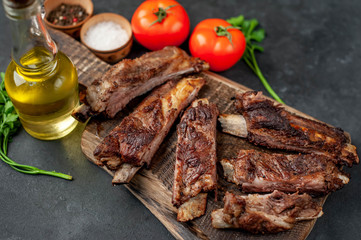 pork ribs with spices, tomatoes and herbs on a stone background