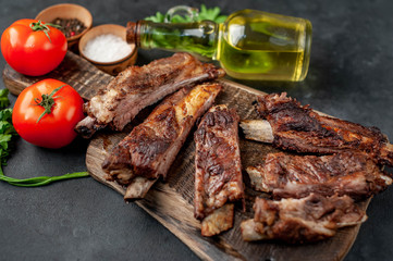 pork ribs with spices, tomatoes and herbs on a stone background