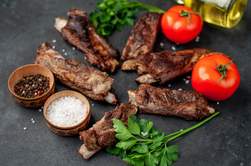pork ribs with spices, tomatoes and herbs on a stone background