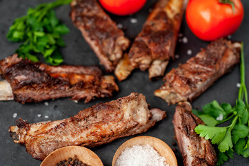 pork ribs with spices, tomatoes and herbs on a stone background