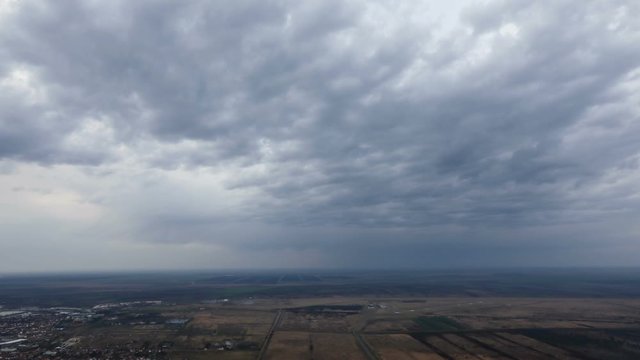 TIME LAPSE of a rainy clouds above the plain and agricultural fields taken from a height