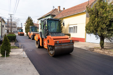 Workers with machines and rollers pave the new road