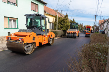 Workers with machines and rollers pave the new road