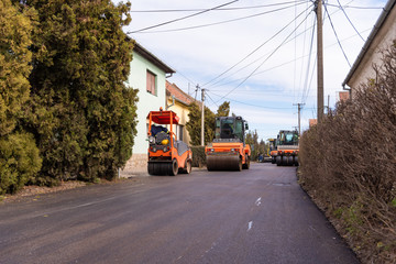 Workers with machines and rollers pave the new road