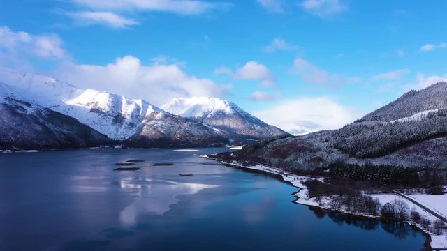 aerial drone footage of winter in glencoe and and loch Leven in the argyll region of the highlands of scotland showing clear bright white snow on the mountains of glencoe and the surrounding region