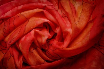Red wavy silk drapery, crumpled fabric swirl rose shape.