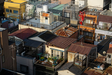 Urban view of Tokyo, Japan. Typical local neighborhood with a lot of tiny houses. City aerial panorama with roofs and an top roofs with emergency stairs and terraces. Sunny day. Colorful buildings.