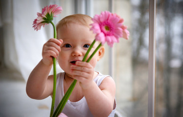 white little girl with pink flowers near the window, portrait of a child