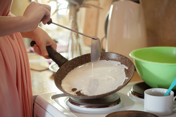 Woman is cooking a pancakes on a frying pan close up.