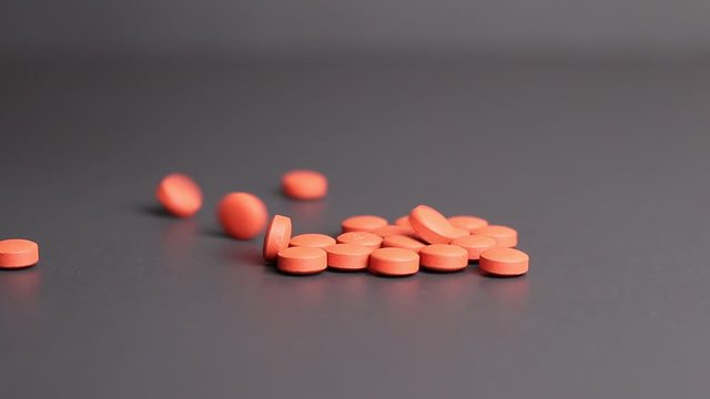 Ibuprofen tablets pills falling and landing on black studio background NSAID or nonsteroidal anti-inflammatory drug illustrative pills medical or pharmaceutical copy space