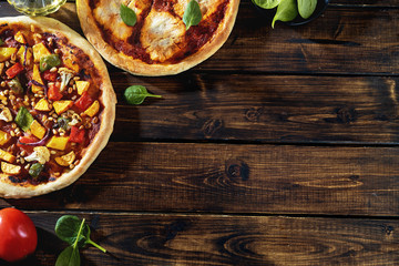 Top view of two vegan pizzas on dark rustic background