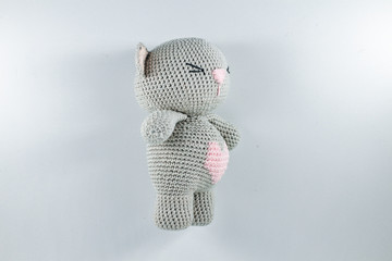 a small knitted toy grey bear cub with a pink heart on its belly