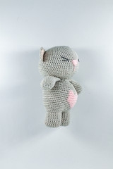 a small knitted toy grey bear cub with a pink heart on its belly
