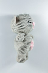 a small knitted toy grey bear cub with a pink heart on its belly