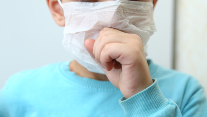 Sick Child wearing surgical mask coughing . Kids wear health masks to prevent germs and dust. Thoughts about health care