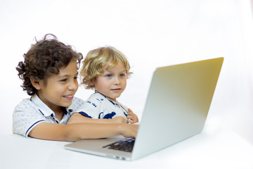 Two cheerful children 4 and 9 years old, using a computer sitting at a desk