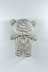 a small knitted toy grey bear cub from the back