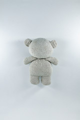a small knitted toy grey bear cub from the back