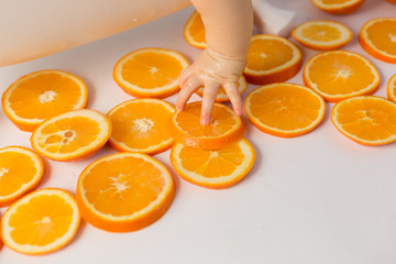 the child is holding a slice of orange orange. child's hand. fruits