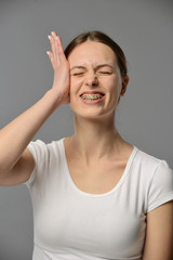 Fototapeta premium portrait of a young girl with braces in a white T-shirt on a gray background