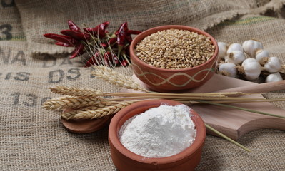 Flour and wheat ears, with grain in clay pot background and texture