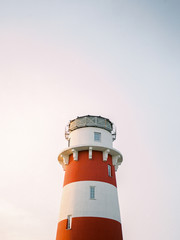 View of white and red lighthouse on clear sky at the sunset