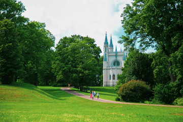 building of a white chapel with blue spiers and a road in a green park leading to it