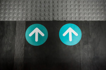 White and Blue Color Arrow Sign as Direction Symbol placed on Floor