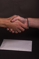 handshake between business men after handing over an envelope
