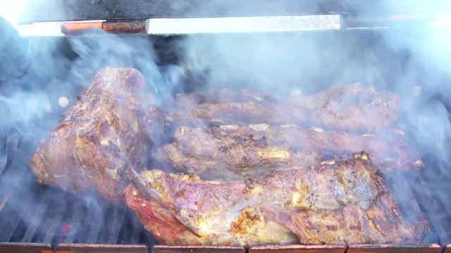 Pork bbq ribs on smoker grill with smoke on charcoal grilling in fire on a grill outside picnics