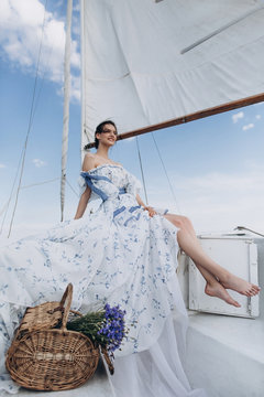 ?oung girl stands on a yacht with white sails in a flying dress.