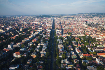 Drone perspective of Andrassy street at sunrise and the skyline of Budapest at background