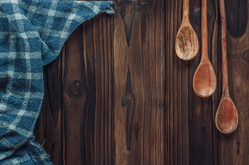 Wood background with plaid fabric, cutting board and wooden spoons