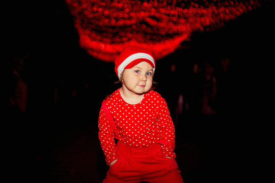 A little, beautiful girl in red clothes and a cap.