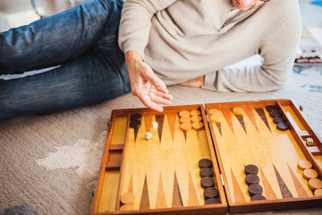 A man plays backgammon lying on the floor - rolls dice