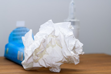 Close-up of paper tissue and nasal spray on a nightstand used during cold, flu or virus. Concept for medical conditions such as annual cold, flu or virus indection to cure at home.