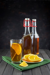 Kombucha superfood pro biotic tea fungus beverage in glass jar with orange on dark background. with green textile