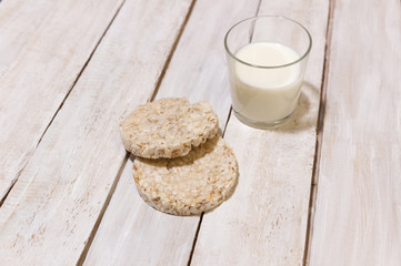  crisp bread of mix cereals and glass of milk  on white wooden  background