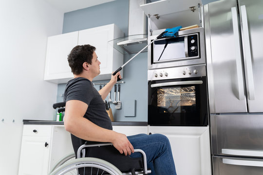 Disabled Man Using Grabber Tool In Kitchen