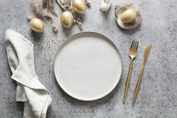 Elegant easter table setting with golden eggs on grey. Top view.