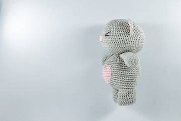 a small knitted toy grey bear cub with a pink heart on its belly
