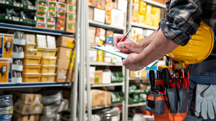 Electrician in the electrical components store writes on the notebook. Construction industry, electrical system.
