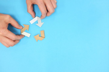 Recycling symbol made of cardboard paper flat lay composition. Blue background with copy space.