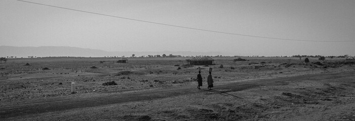 Two Massai women walking along the road in the wide East-African plateau